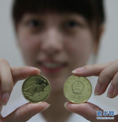 　　9月23日，在上海金山区象州路上的一家农业银行，一名工作人员正在展示“和”字书法——行书普通纪念币。新华社发(庄毅 摄)
