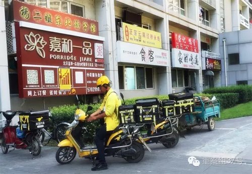 2016年7月26日，通州区北京像素小区，一栋楼的一楼开了密集的餐馆，餐馆外停着美团的外卖车，一名送餐员正要骑车去送餐。